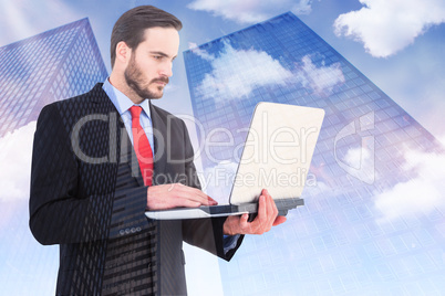 Composite image of focused businessman using his laptop