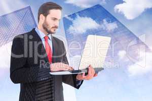 Composite image of focused businessman using his laptop