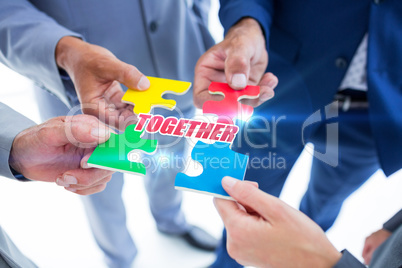 Together against business colleagues holding piece of puzzle