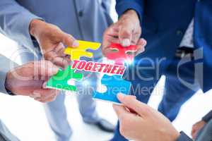 Together against business colleagues holding piece of puzzle