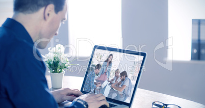 Composite image of businessman using laptop at table in office