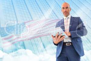 Composite image of businessman using a tablet and smiling at the