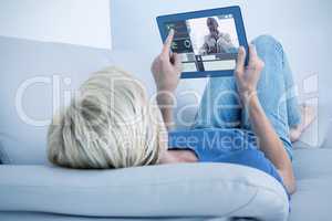 Composite image of blonde woman using her tablet on the couch