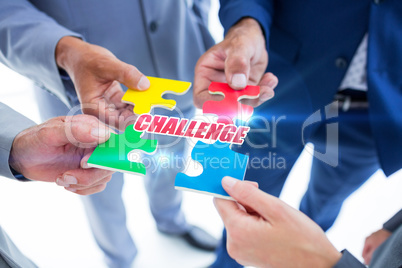 Challenge against business colleagues holding piece of puzzle