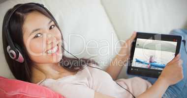 Composite image of girl using her tablet pc on the sofa and list