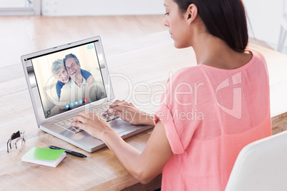 Composite image of businesswoman using laptop at desk in creativ