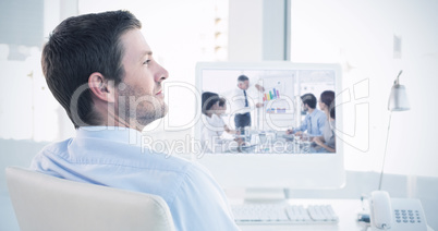 Composite image of smiling businessman sitting at his desk