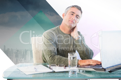 Composite image of businessman with neck pain using laptop at de