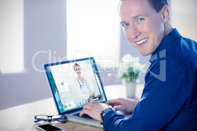 Composite image of smiling businessman using laptop in office