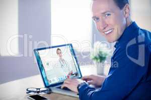 Composite image of smiling businessman using laptop in office