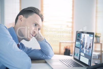 Composite image of focused businessman looking at laptop