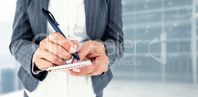 Composite image of midsection of businesswoman writing on notepa