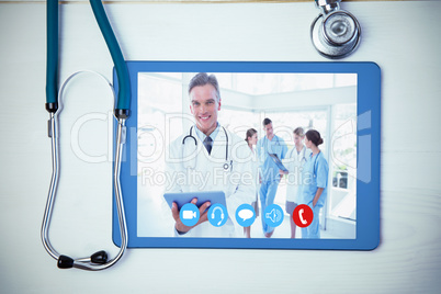 Composite image of smiling doctor holding digital tablet