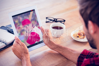 Composite image of rear view of man using tablet on wooden table