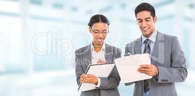 Composite image of smiling business people writing on clipboard