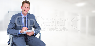 Composite image of businessman writing down on a notebook