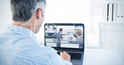 Composite image of man with grey hair using his laptop