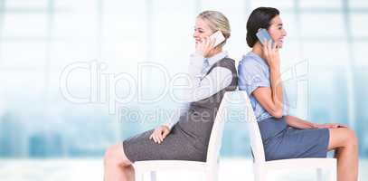 Composite image of businesswomen using smartphones while sitting