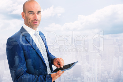 Composite image of businessman using a tablet and smiling at the