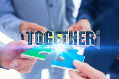 Together against business colleagues holding piece of puzzle