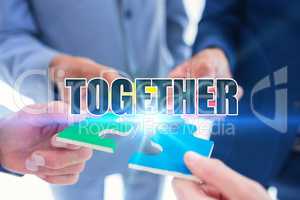 Together against business colleagues holding piece of puzzle