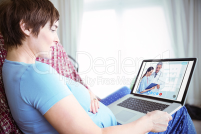Composite image of pregnant woman using her laptop