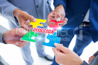 Mission against business colleagues holding piece of puzzle