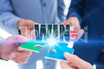 Win against business colleagues holding piece of puzzle