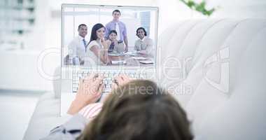 Composite image of woman using laptop while lying on sofa