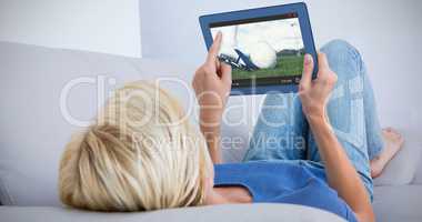 Composite image of blonde woman using her tablet on the couch