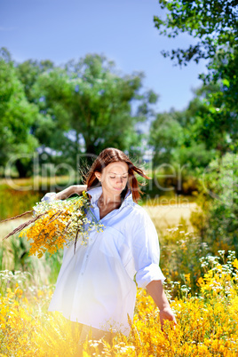 The girl holds a bouquet of wild flowers in hand.
