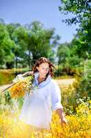 The girl holds a bouquet of wild flowers in hand.