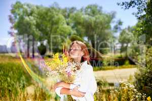 The girl holds a bouquet of wild flowers in hand.