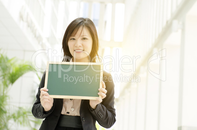 Young Asian business woman holding blank board