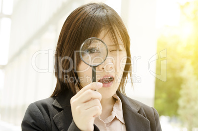Asian female looking through magnifier glass