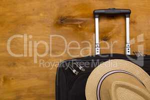 Black traveler suitcase and a straw hat