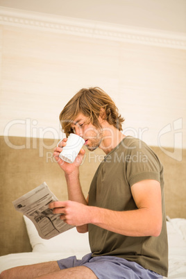 Handsome man reading the news and drinking coffee