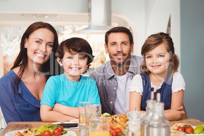 Portrait of cheerful family with food on dining table