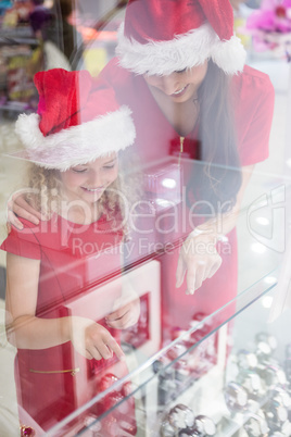 Mother and daughter in Christmas attire looking at wrist watch d