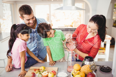 Smiling family with mother pouring fruit juice