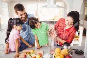 Smiling family with mother pouring fruit juice