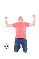 Excited man shouting with fist up and a soccer ball