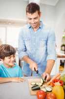 Happy man chopping vegetable with son