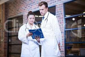 Two doctors looking at clipboard and discussing near library