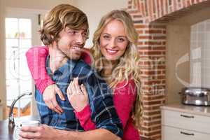 Cute couple cuddling with girlfriend sitting on the counter