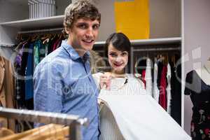 Portrait of couple selecting a dress while shopping for clothes