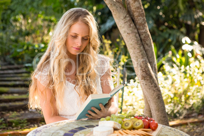 Beautiful blonde relaxing and reading with food