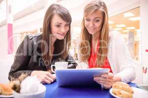 Women using digital tablet while having coffee and snacks