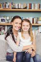 Cheerful mother sitting with daughter on sofa