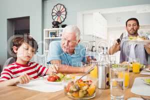 Granddad talking to grandson while sitting at dining table
